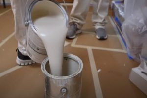 Worker pouring paint in the bucket